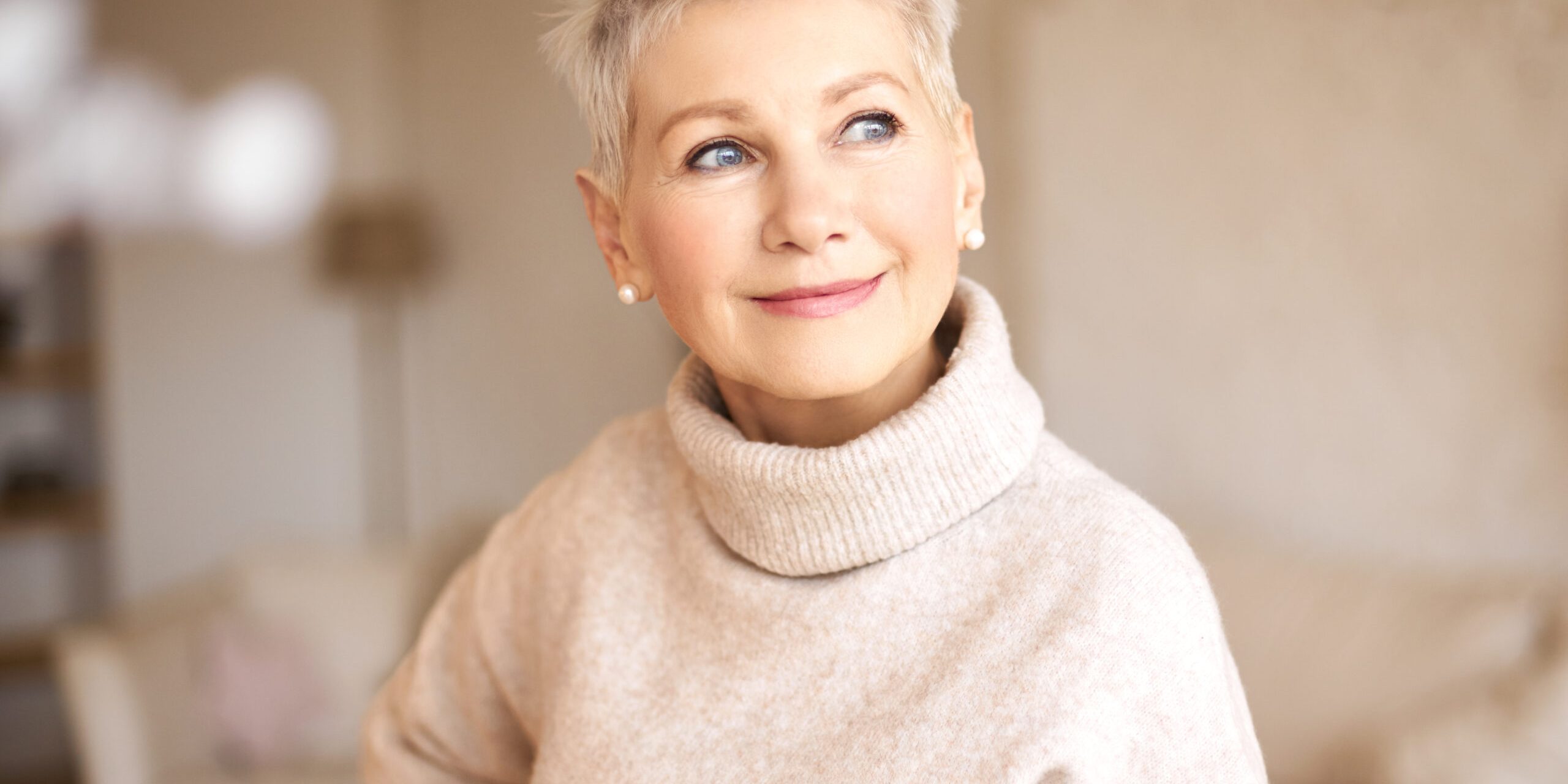 People, age and maturity. Close up shot of elegant blonde middle aged woman with short haircut looking up with pensive smile, thinking about something pleasant, making plans, recollecting old days healthy aging
